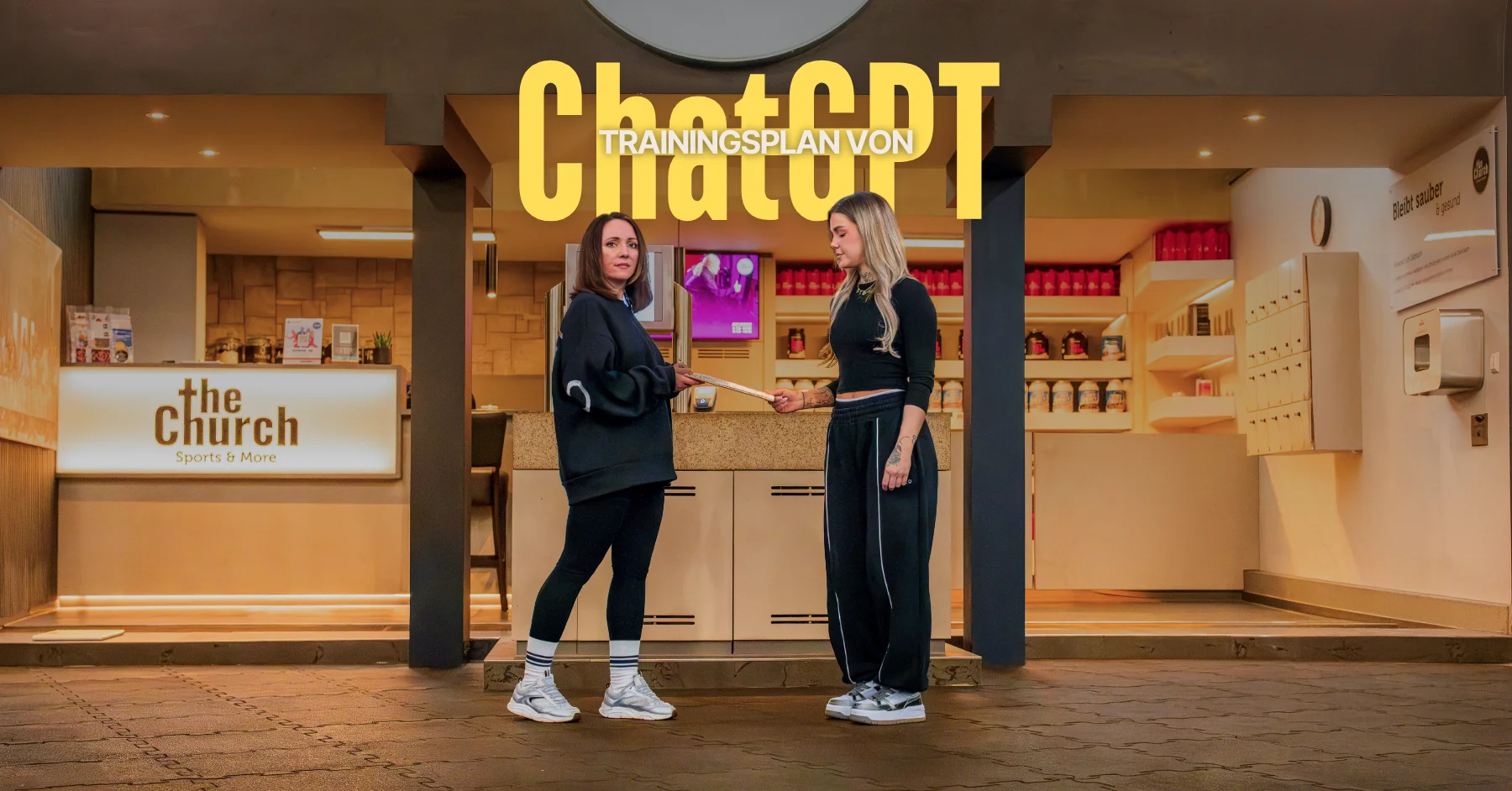 Trainingsplan von ChatGPT Zwei Frauen im Fitnessstudio „The Church“, die ein Tablet mit einem Trainingsplan von ChatGPT halten.