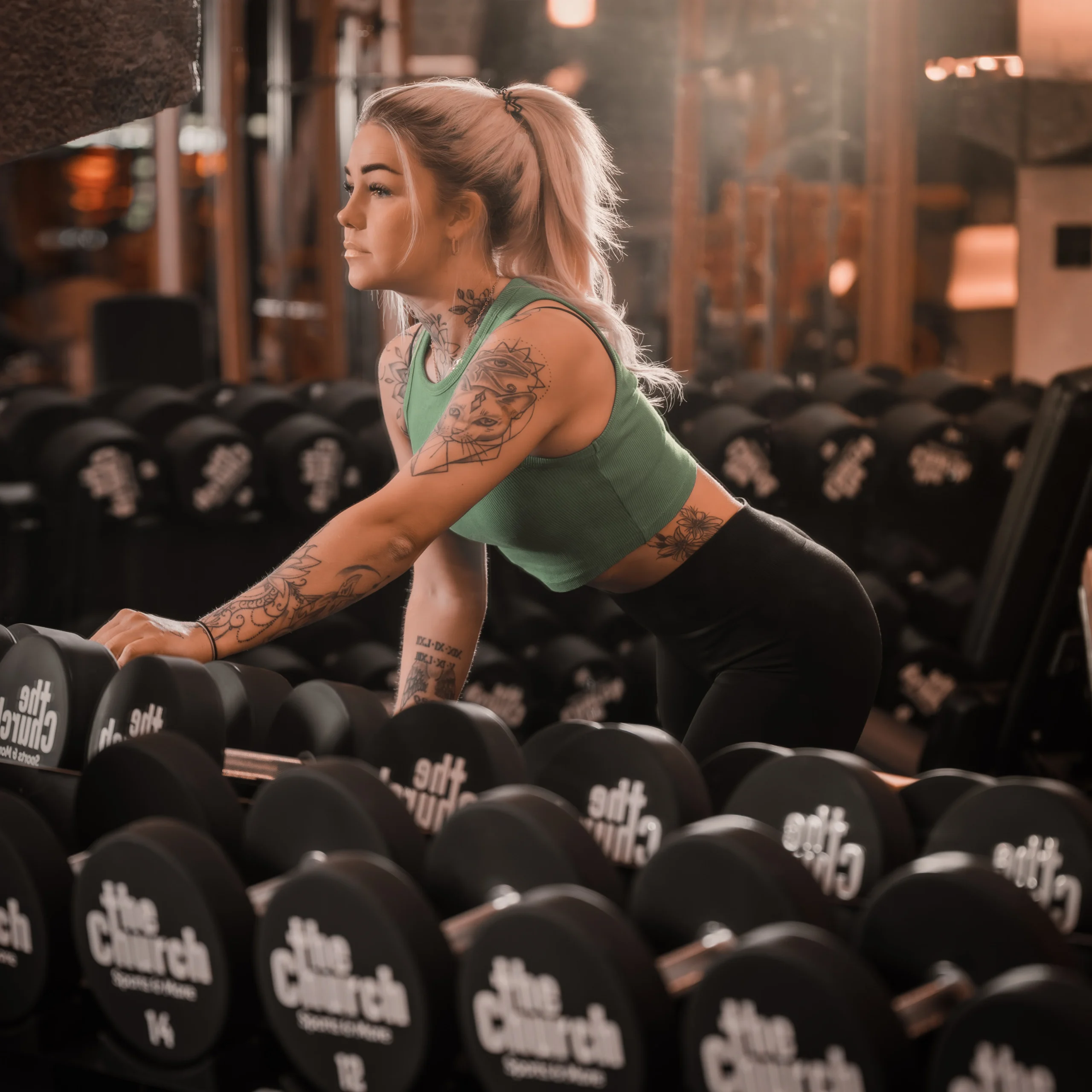 ava_202603121 Eine tätowierte Frau bereitet sich im Studio auf die Übungen vor.